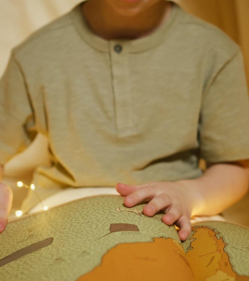 A young boy deeply absorbed in reading an illustrated storybook indoors.