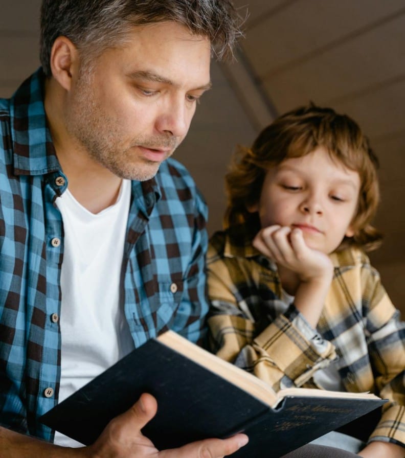 A father and son sharing a tender moment reading a bedtime story together.
