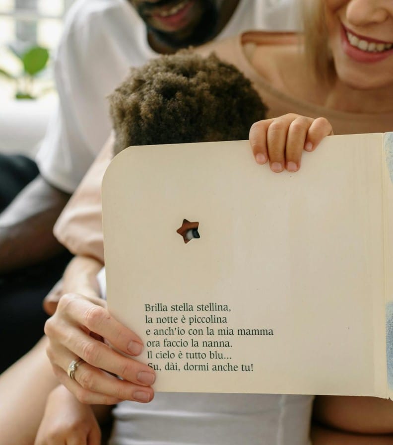 A joyful family reading a children's storybook together indoors, showcasing affection and warmth.