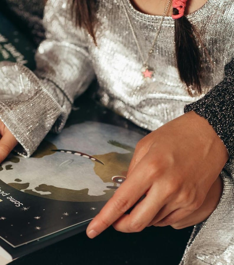 A child reads a colorful storybook with an adult's guidance, learning and bonding.