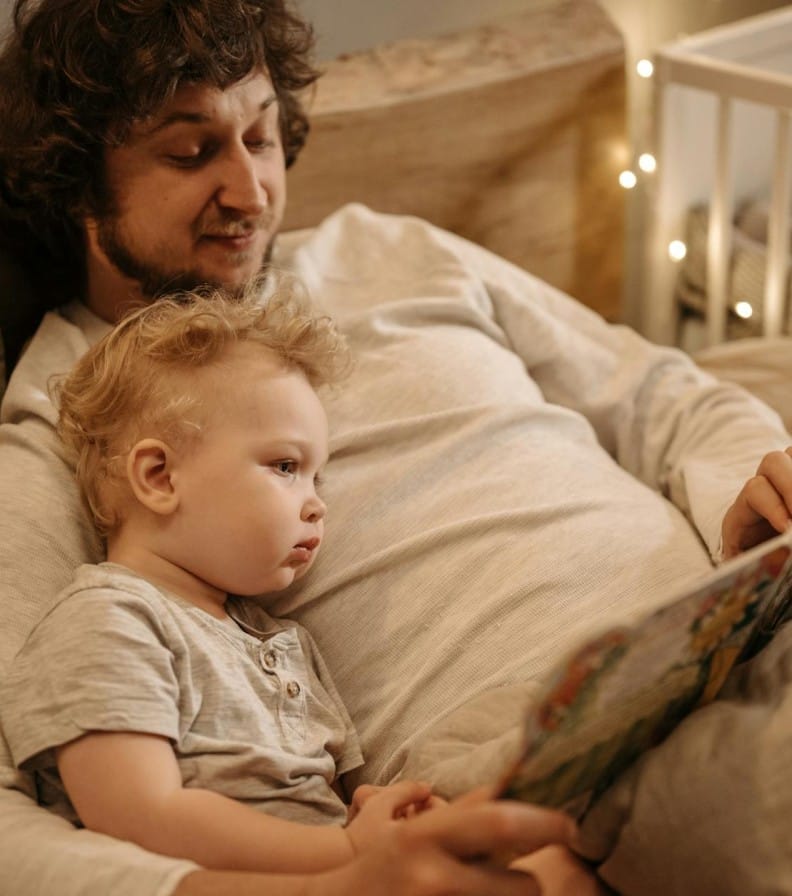 A father and child share a warm moment reading together before bedtime.